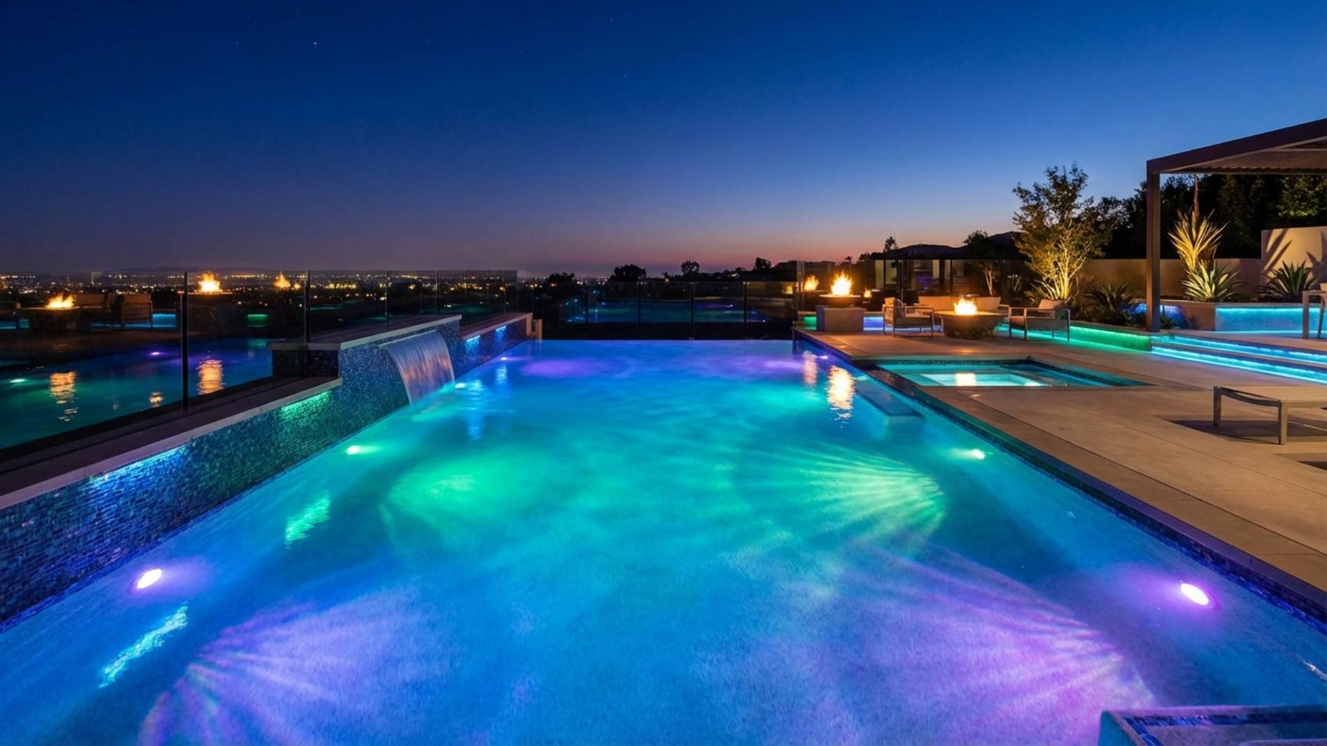 Fotografía nocturna de una piscina moderna iluminada con luces LED subacuáticas de color azul cristalino